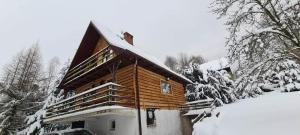 Cabaña de madera con nieve en el techo en Domek na kurzej stópce, en Grzechynia