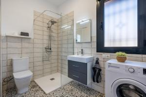 a bathroom with a toilet and a sink and a washing machine at La Parva - Casa rural Eralta in Dúrcal