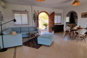 a living room with a blue couch and a table at Villa à la campagne avec vues, piscine, jaccuzi, sauna in Alora