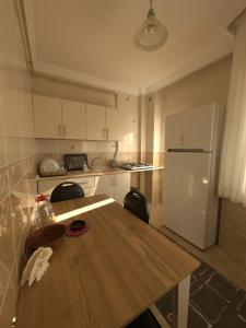 a kitchen with a wooden table and a white refrigerator at BEŞ YILDIZ APART in Trabzon