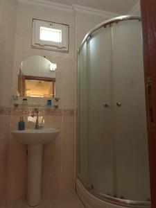 een badkamer met een douche, een wastafel en een spiegel bij BEŞ YILDIZ APART in Trabzon