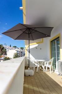 een zwarte parasol op een balkon met een tafel en stoelen bij Apartamento Karibu in Carvoeiro