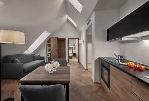 a kitchen and living room with a couch and a table at Hotel Schwarzer Adler Innsbruck in Innsbruck