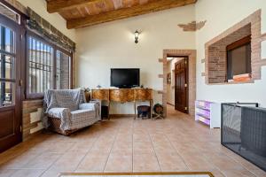 ein Wohnzimmer mit einem TV, einem Tisch und Stühlen in der Unterkunft Mas del Vedell in L'Ampolla