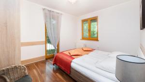 a white bedroom with a bed and a window at Apartamenty Sun & Snow Poronin in Poronin