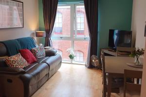 a living room with a leather couch and a television at A Superb One Bed Apt In The Heart Of The City in Nottingham