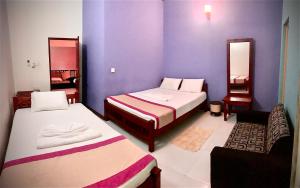 two beds in a room with purple walls at Cinnamon Tree Tourist Rest in Anuradhapura
