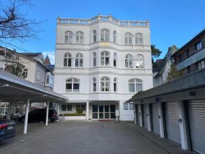 a white building with a parking lot in front of it at Villa Sirene Whg 4 Königsstuhl - 5 Sterne in Binz