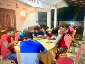 a group of people sitting at a table eating food at Cinnamon Tree Tourist Rest in Anuradhapura