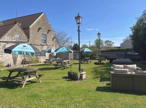 a group of picnic tables and an umbrella in the grass at The Bell at Old Sodbury in Chipping Sodbury