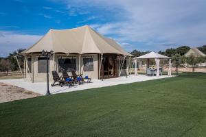 Tienda con sillas y mesas en un campo en El Toril Glamping Experience, en Parrillas