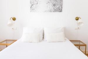 um quarto com uma cama branca e almofadas brancas em City Centre TEATRO em Málaga
