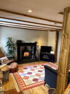 a living room with a fireplace and a rug at Charming, rustic & well equipped garden cottage in Alyth
