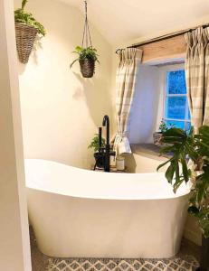 a white bath tub in a bathroom with plants at Charming, rustic & well equipped garden cottage in Alyth