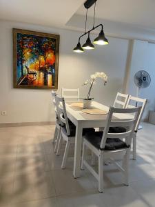 Biały stół jadalny z białymi krzesłami i obrazem w obiekcie Beautiful Apartment Casa Mundo Aguilón w mieście San Juan de los Terreros