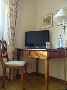 Habitación con escritorio, TV y silla. en Hotel Freihof, en Wiesloch