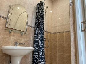 cortina de ducha en el baño con lavamanos en Юкон, en Konopnitsa