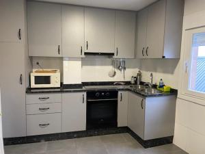 a kitchen with white cabinets and a sink and a microwave at AS REGATEIRAS casa próxima a las termas in Ourense