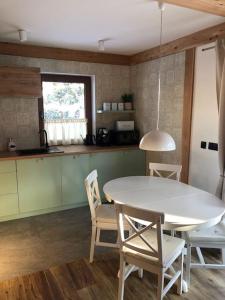 eine Küche mit einem weißen Tisch und Stühlen in einem Zimmer in der Unterkunft RELAS - przytulny domek z dwoma sypialniami i antresolą in Murzasichle