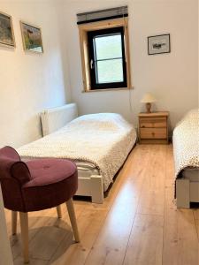 1 Schlafzimmer mit 2 Betten, einem Stuhl und einem Fenster in der Unterkunft Töpferweg 06 Doppelhaushälfte Mia in Ahrenshoop