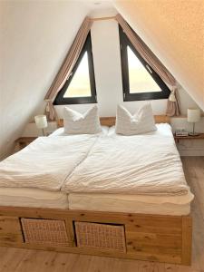 ein großes Bett in einem Zimmer mit zwei Fenstern in der Unterkunft Töpferweg 06 Doppelhaushälfte Mia in Ahrenshoop