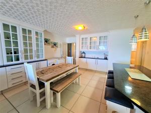 Una cocina con una mesa de madera y gabinetes blancos. en Santorini 203A, en Margate