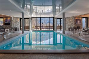 a large swimming pool in a building with windows at Les Granges d'en Haut - Chamonix Les Houches in Les Houches