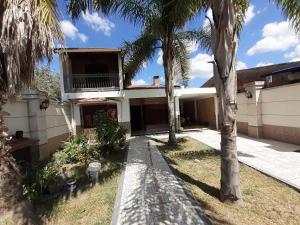 a house with palm trees in front of it at Hospedate en nuestro hogar y disfruta unas lindas vacaciones en Termas de Rio Hondo in Termas de Río Hondo