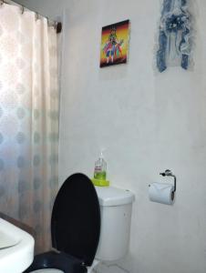 a bathroom with a white toilet with a black seat at Cafetín-Hostal Rincón NICA in Granada