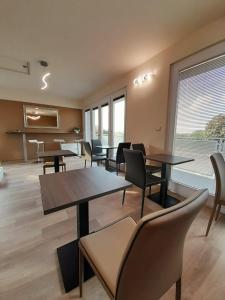 una sala d'attesa con tavoli, sedie e finestre di Prealpina Hotel a Bagnolo Piemonte