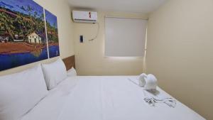 a bedroom with a white bed with a painting on the wall at Arena Carneiros Hotel by AFT in Tamandaré