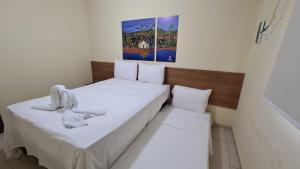 two beds in a small room with white sheets at Arena Carneiros Hotel by AFT in Tamandaré