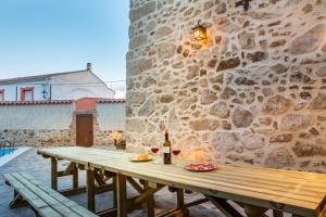 - une table en bois avec une bouteille de vin à côté d'un mur en pierre dans l'établissement El Pelaor, à Benquerencia