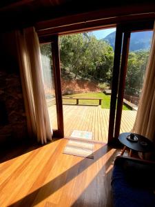 a room with a large glass door to a deck at Casa Cacau Boutique B&B - Sítio Salamandra, Vale do Matutu in Aiuruoca