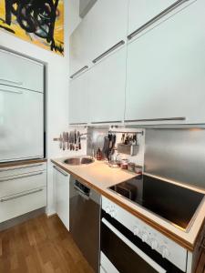 a kitchen with white cabinets and a sink and a stove at Art Loft in downtown Oslo with Home Cinema in Oslo