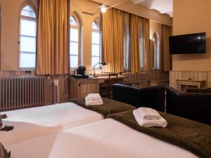 a hotel room with two beds and a desk at Hotel Monasterium PoortAckere Ghent in Ghent