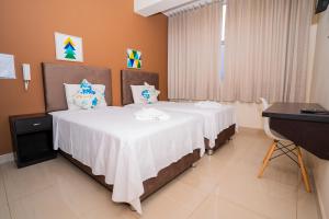 een slaapkamer met een bed met witte lakens en een bureau bij Tropical City in Tarapoto