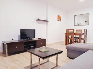 ein Wohnzimmer mit einer Couch, einem Fernseher und einem Tisch in der Unterkunft Apartamentos Turísticos Taymar in Chiclana de la Frontera