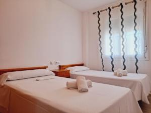 ein Zimmer mit zwei Betten mit Handtüchern darauf in der Unterkunft Apartamentos Turísticos Taymar in Chiclana de la Frontera + 13 Fotos