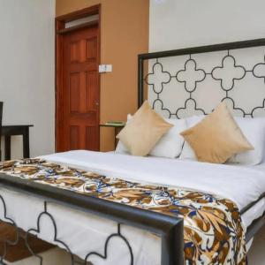 sypialnia z dużym łóżkiem z czarno-białym zagłówkiem w obiekcie Naalya Motel w mieście Kampala