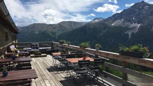 une terrasse avec des tables et des chaises et des montagnes en arrière-plan dans l'établissement Alp Es-Cha Dadour, à Madulain