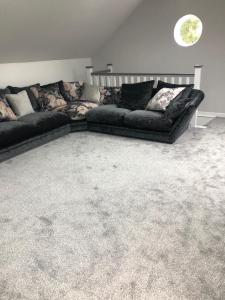 ein Wohnzimmer mit einer schwarzen Couch und einem Teppich in der Unterkunft The Annexe at Bricket House in Malvern Link