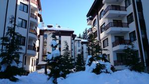 a pile of snow in front of two buildings at TES Flora Apartments in Borovets