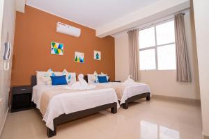 2 camas en una habitación con paredes de color naranja en Tropical City en Tarapoto