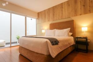 1 dormitorio con 1 cama grande y ventanas grandes en Spectacular 1BR in Miraflores, en Lima