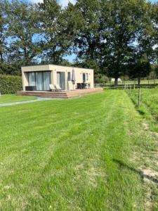 a small house in the middle of a grass field at Chalet Unique in Oldeberkoop