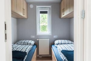 two beds in a small room with a window at Chalet Unique in Oldeberkoop