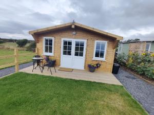 a small wooden cabin with a table and a patio at Bumble Bee Cabin in Bootle