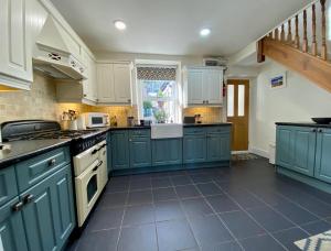 a large kitchen with blue cabinets and a staircase at Llandudno Boutique style seaside retreat with stunning views in Llandrillo-yn-Rhôs