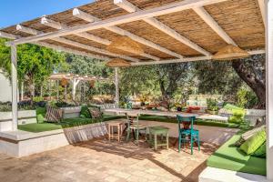 an outdoor patio with green furniture and a wooden pergola at Trulli cicale e olive in Ceglie Messapica